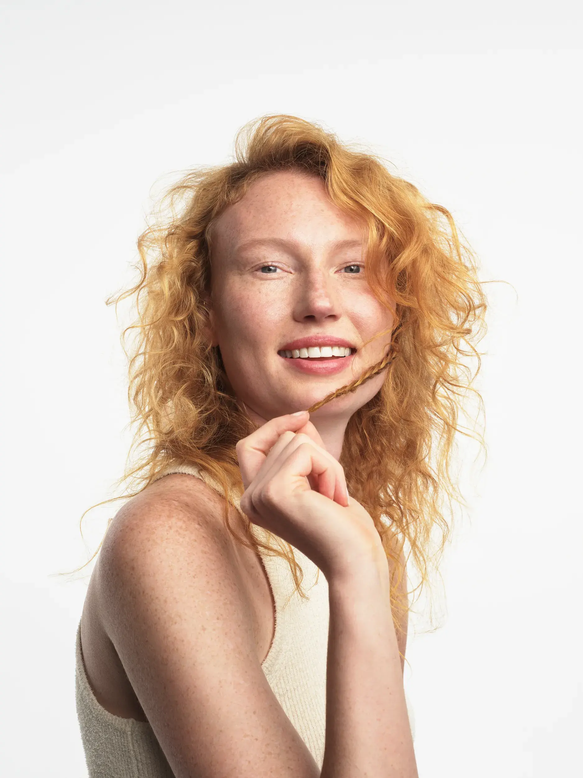 ginger white woman with curly hair holding onto a braid from her hair