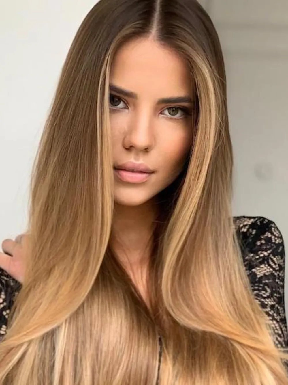 Model with long, straight hair featuring natural blonde balayage, created using Wella Professionals.