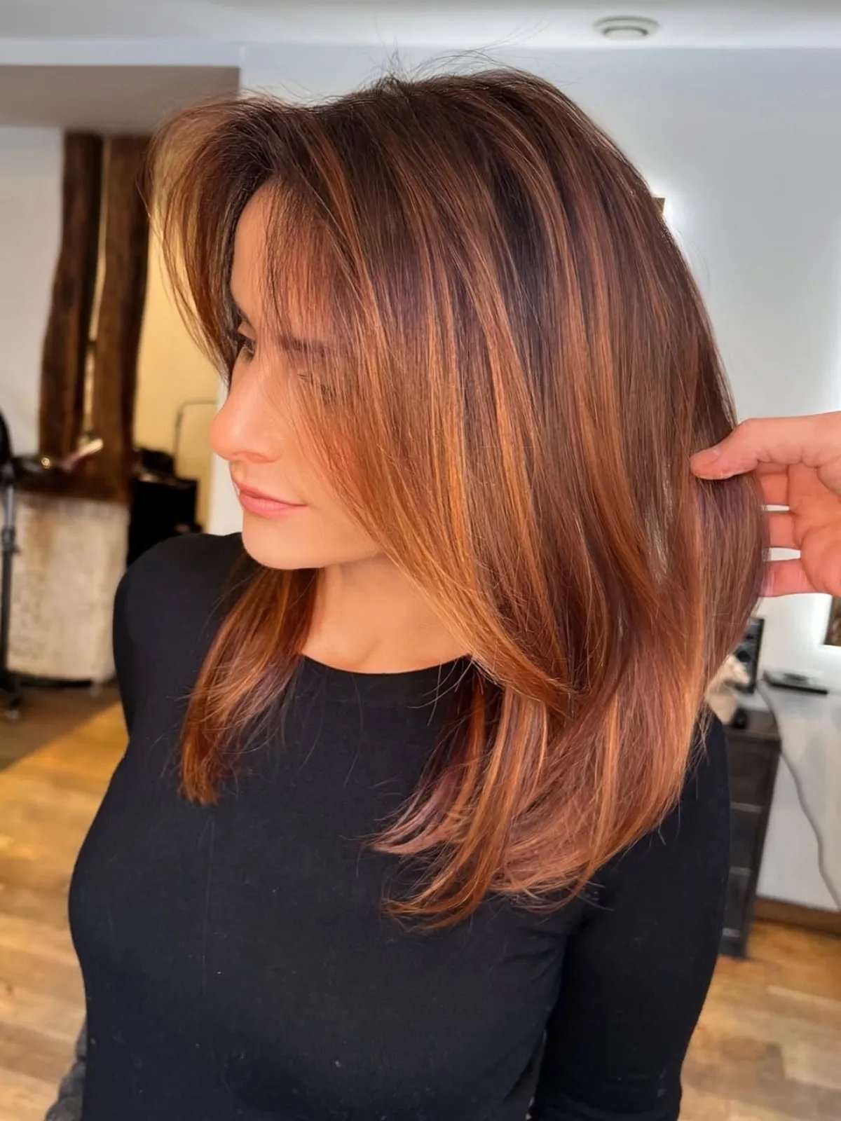 Model with dark brown hair featuring golden auburn highlights.