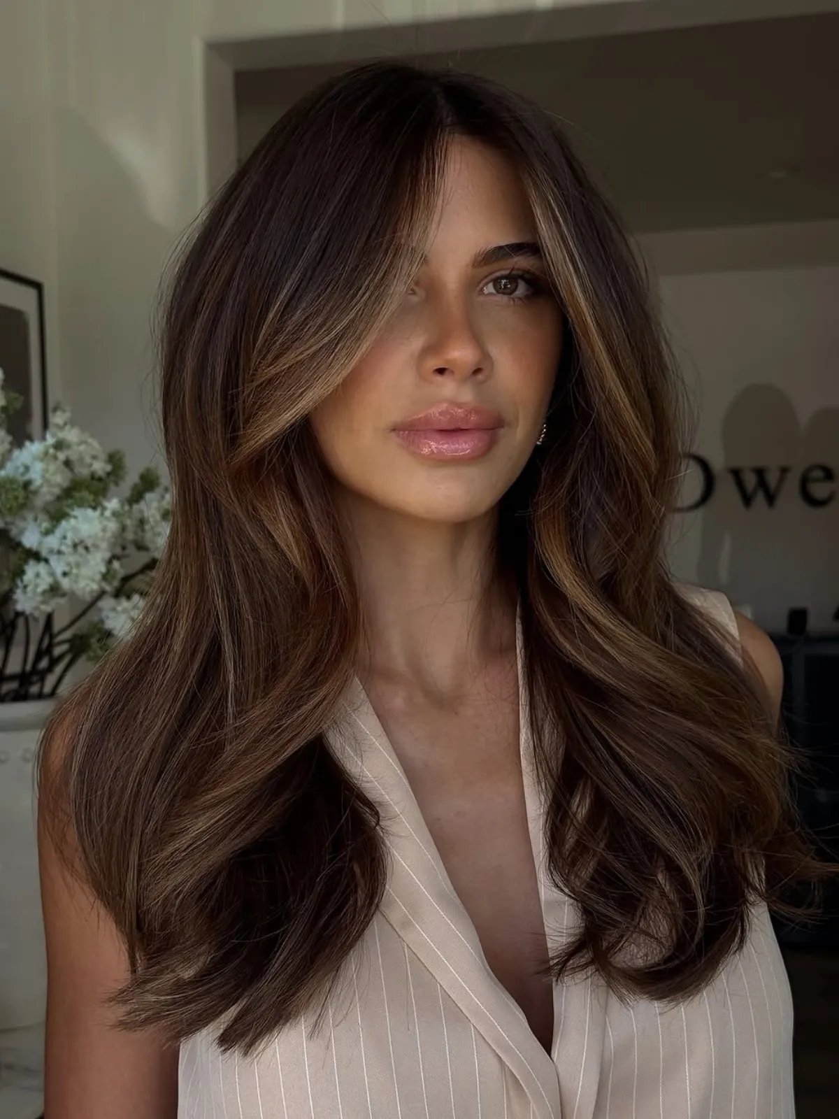 Model with dark brown hair featuring light brown face-framing highlights.