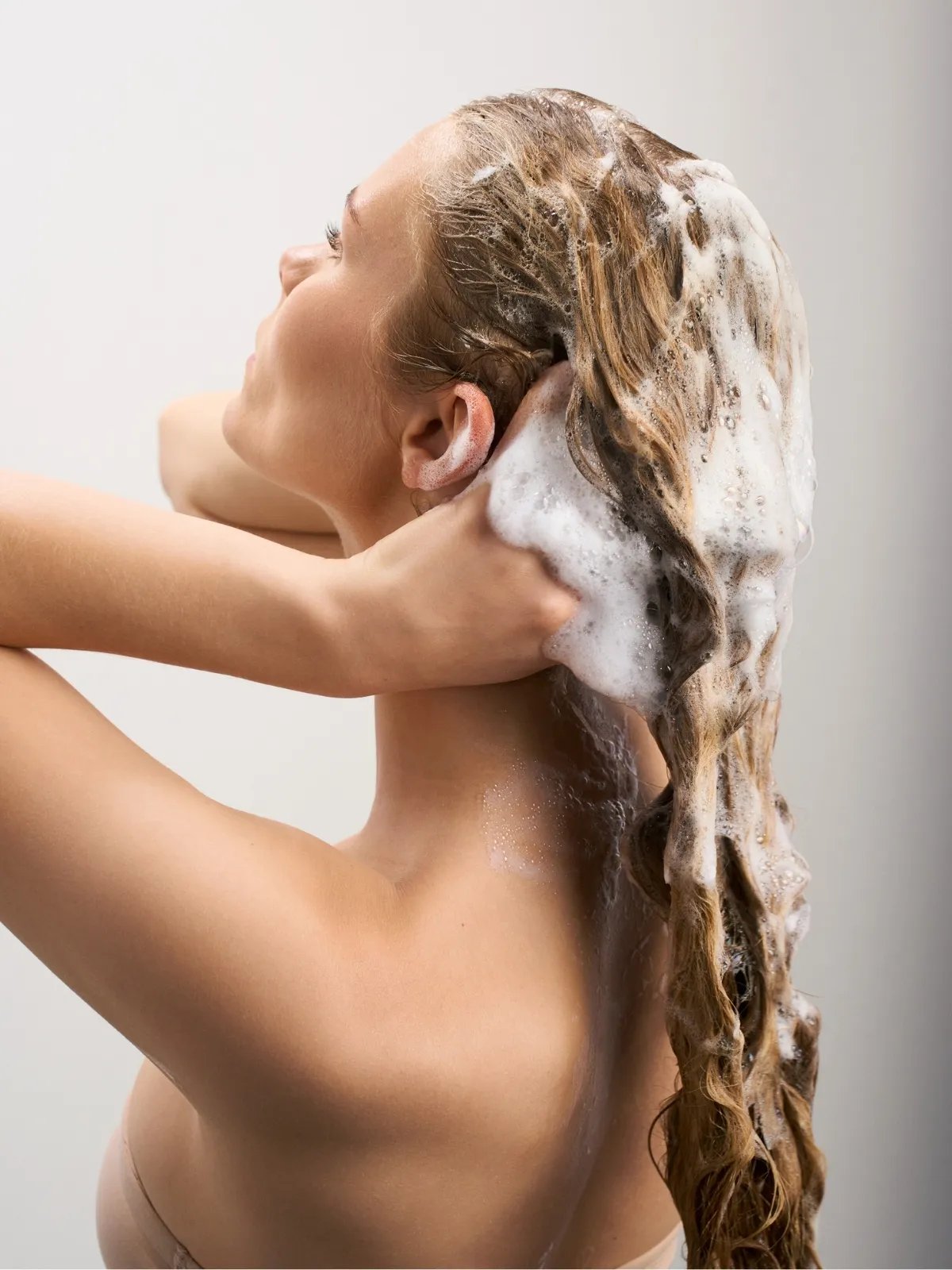 Model massages ULTIMATE SMOOTH Shampoo into wet hair.