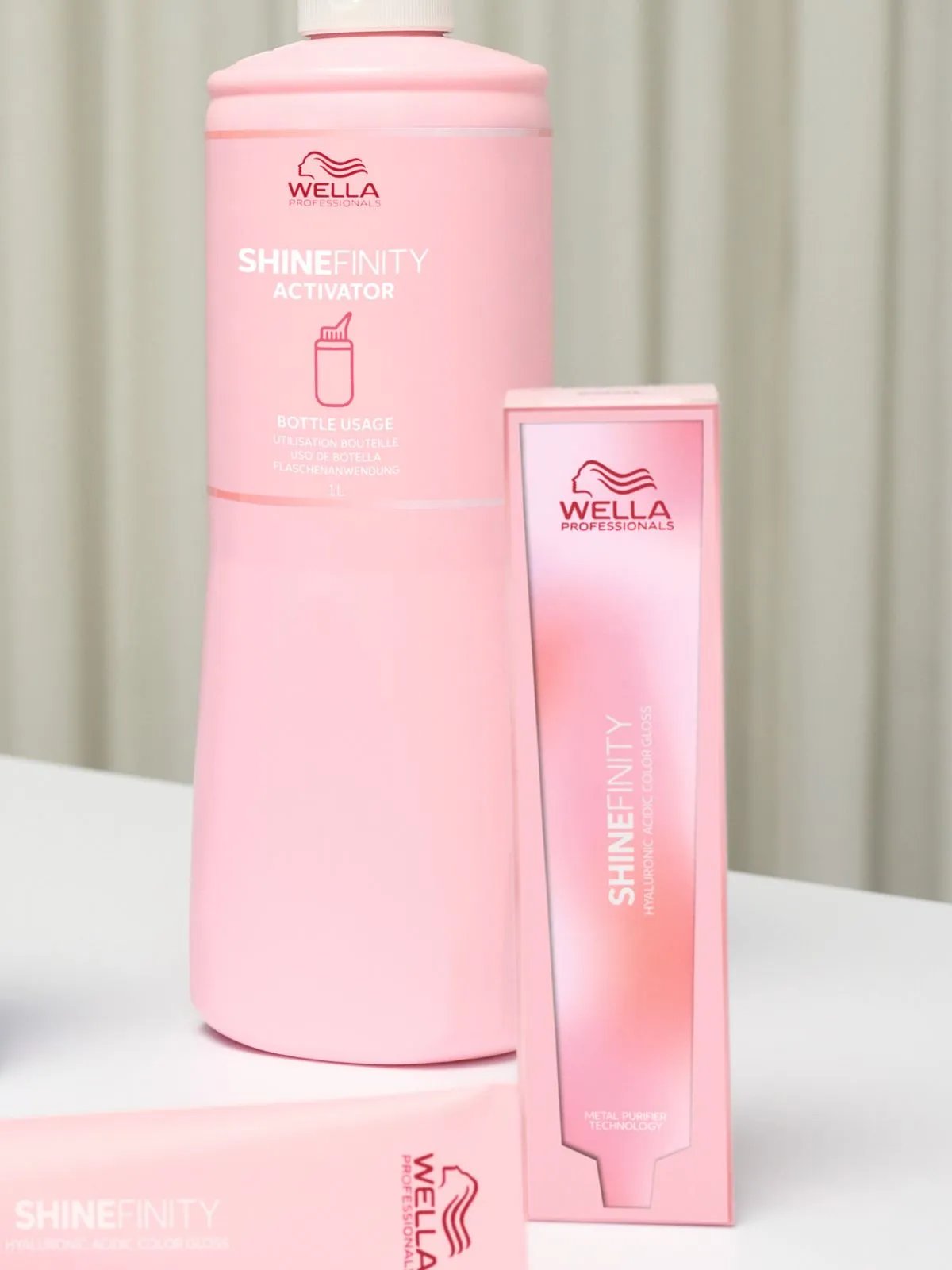 A bottle of SHINEFINITY activator next to a box and tube of SHINEFINITY color.