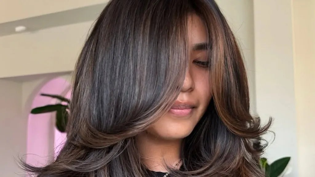 Model with glossy mocha brown hair in soft waves, showcasing rich, multidimensional brunette colour under natural light.