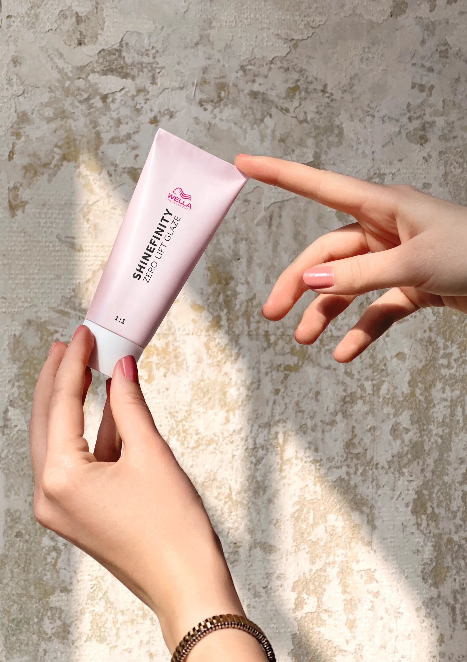 Hand holding a tube of the Wella Shinefinity Glaze