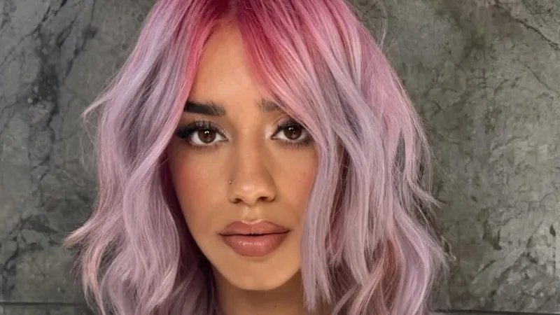Model with pink to purple ombre hair styled in loose waves.