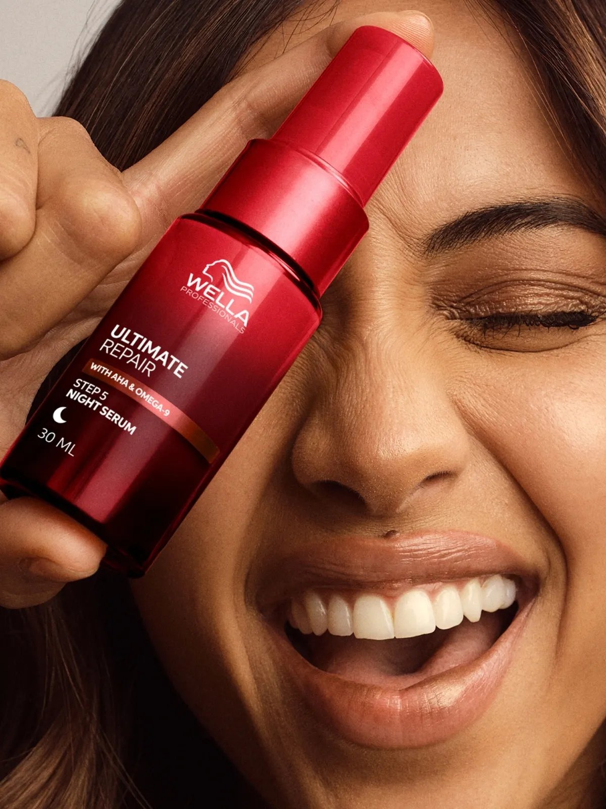 Model holds ULTIMATE REPAIR Night Serum in front of face.