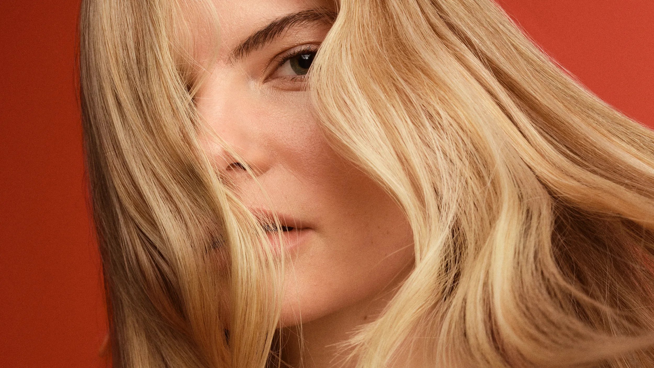 Close-up of a model with blonde hair looking at the camera.