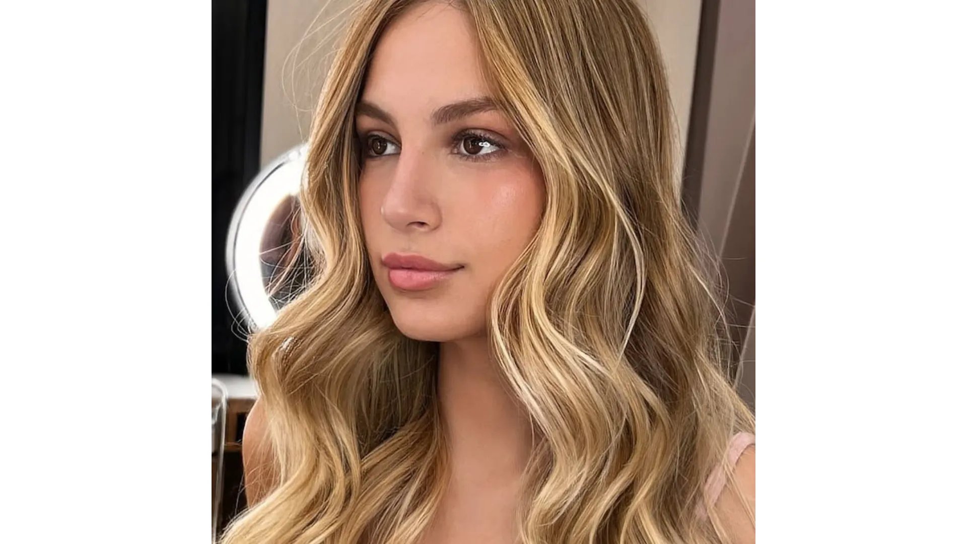 Model with long, ultra-glossy, honey blonde hair styled in loose waves.