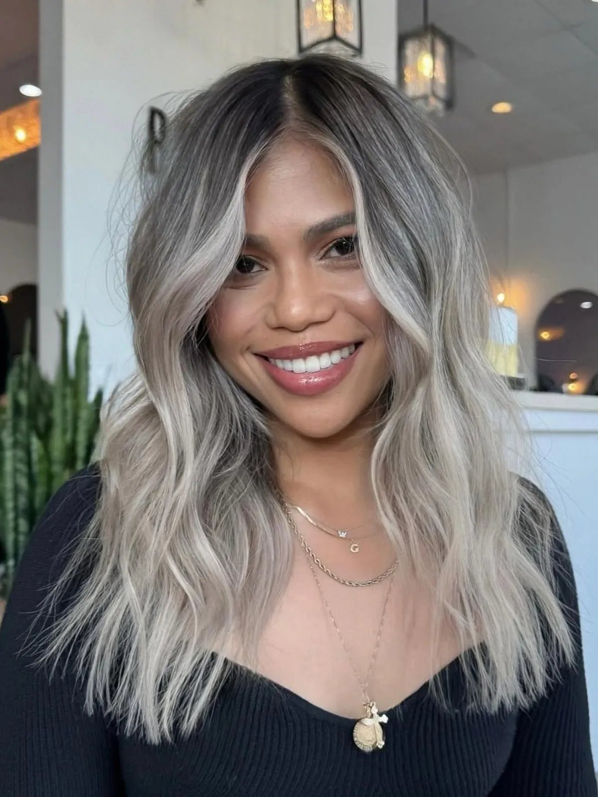 Model with wavy, silver hair featuring a dark shadow root.