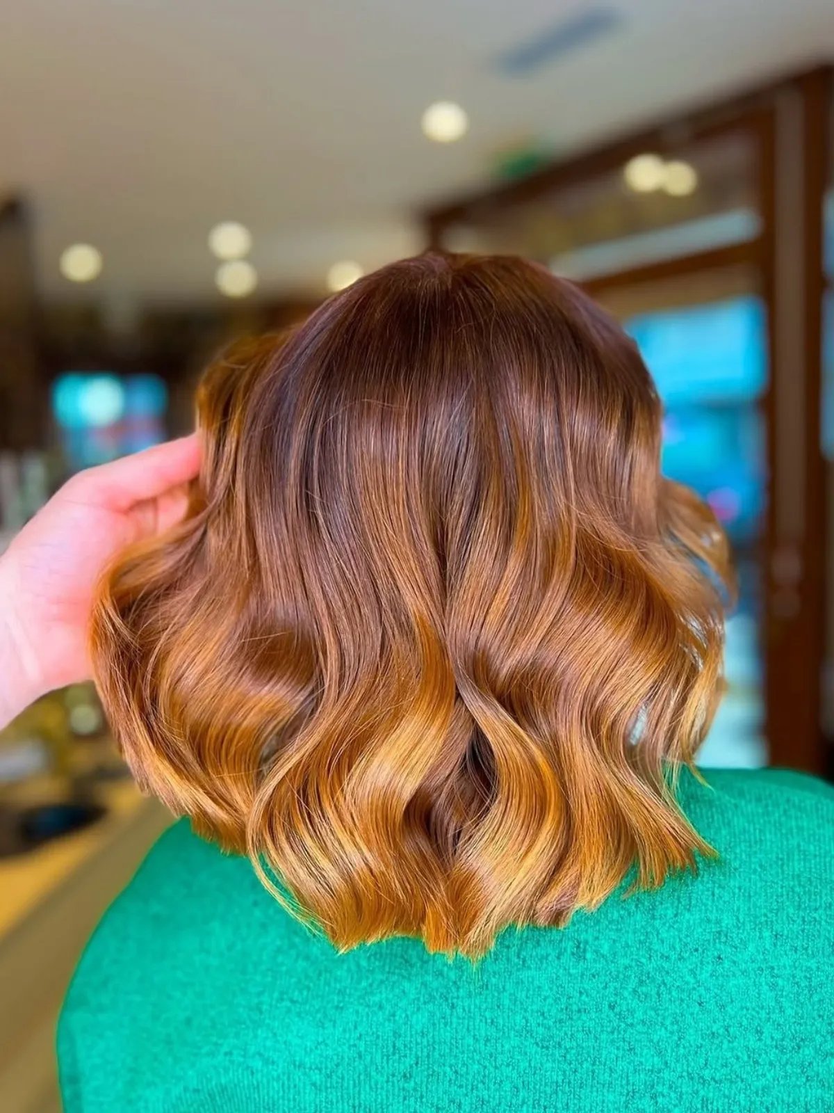 Model with shoulder-length, loosely curled, light copper brown hair.