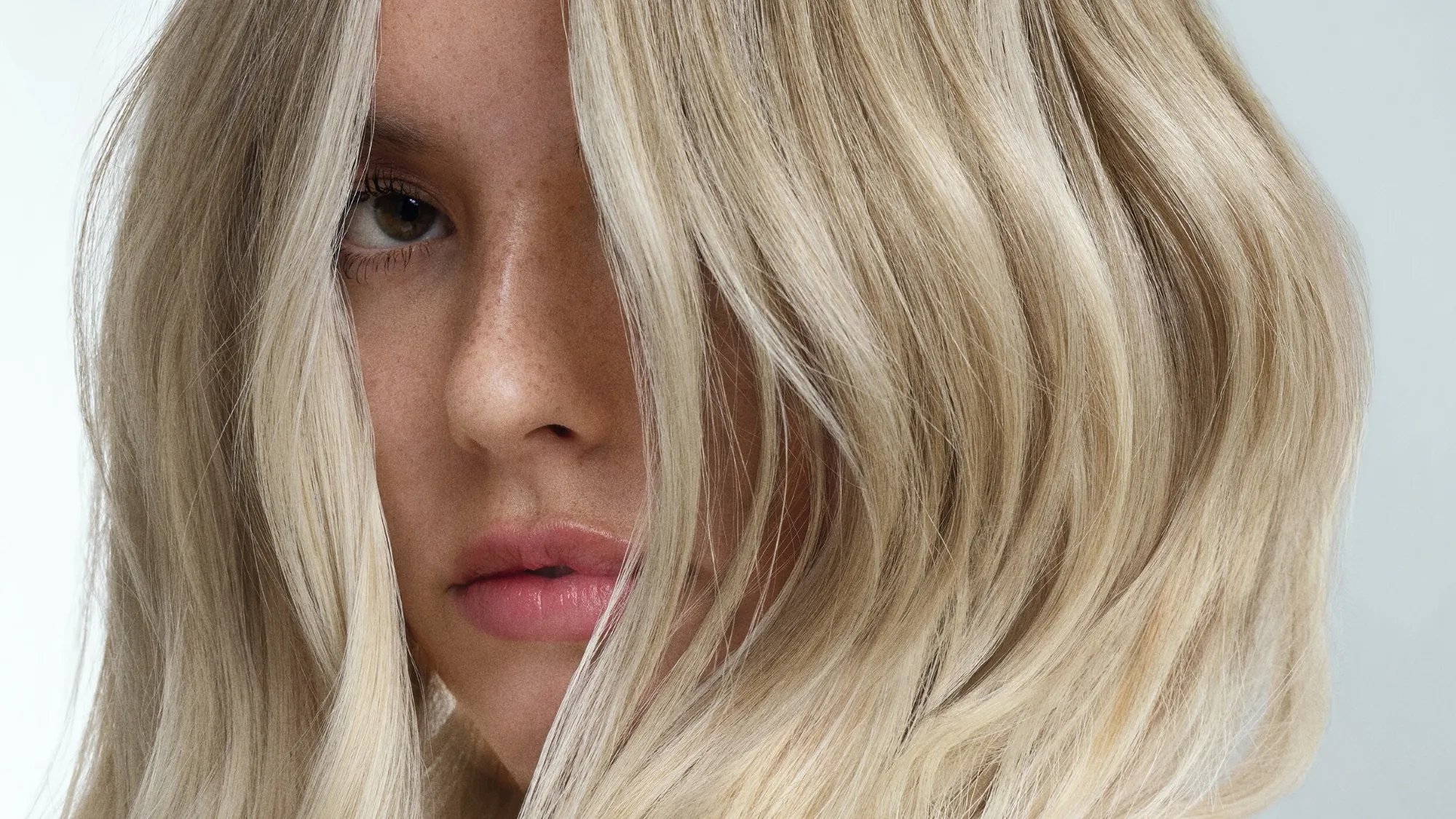 Close-up of model with beachy, tousled, bright blonde hair.