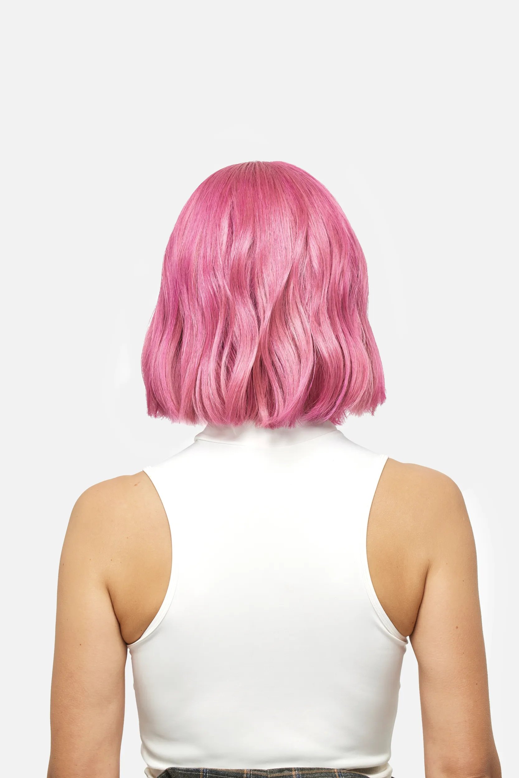 Back of woman's head with short pink hair against a white background.