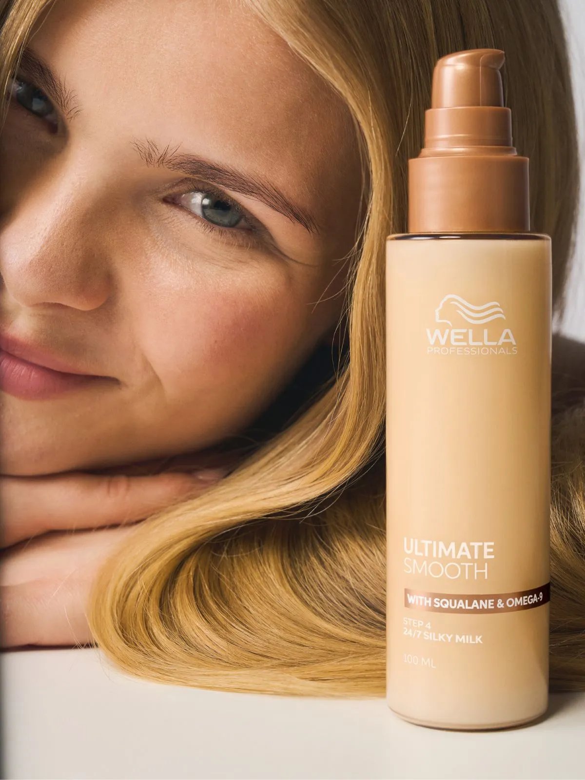 Model with long, smooth, blonde hair next to a bottle of ULTIMATE SMOOTH Silky Milk.