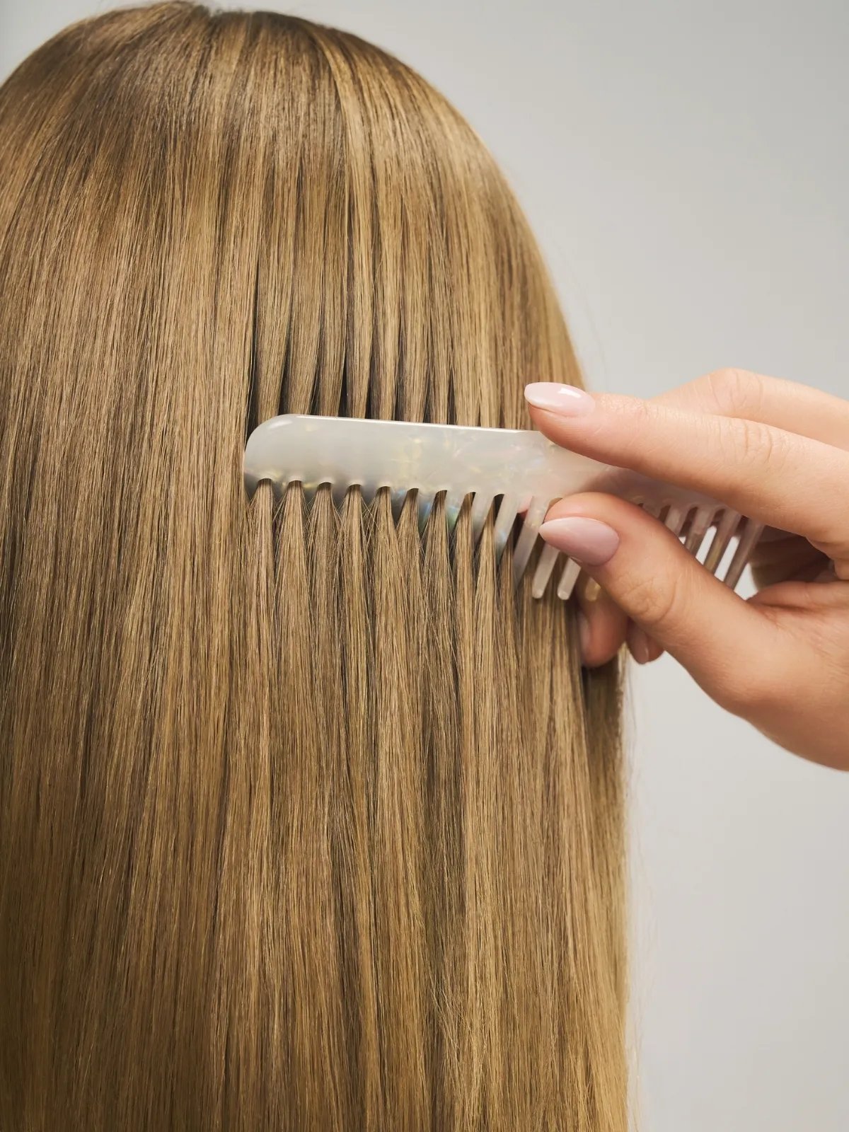 Model runs comb through their long, blonde hair.