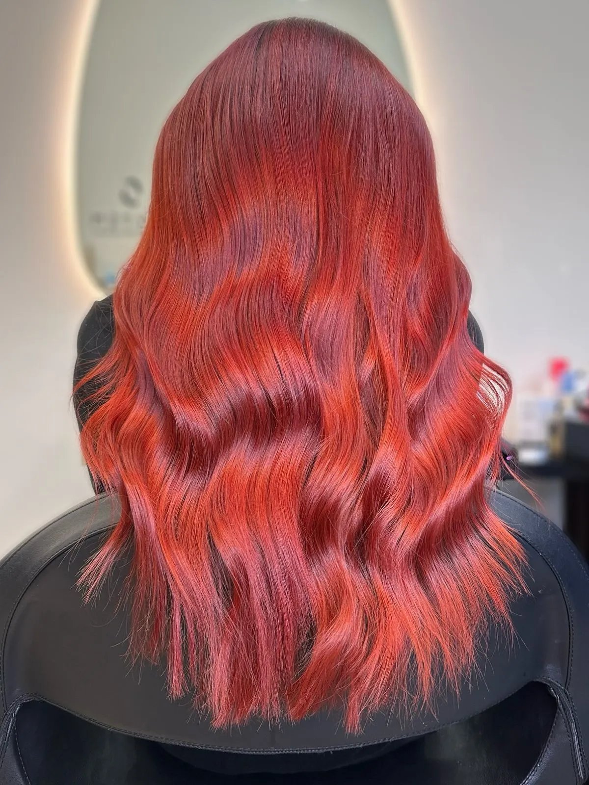 Back of model’s head showing wavy hair in a bright sangria red shade.