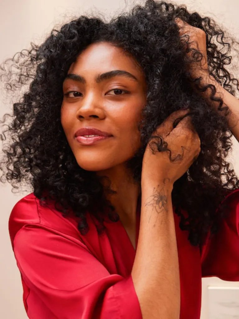 Model smooths ULTIMATE REPAIR Night Serum through dark, curly hair.