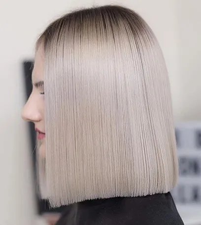 Straight, blunt-cut bob hairstyle with a smooth finish and platinum blonde color featuring darker roots